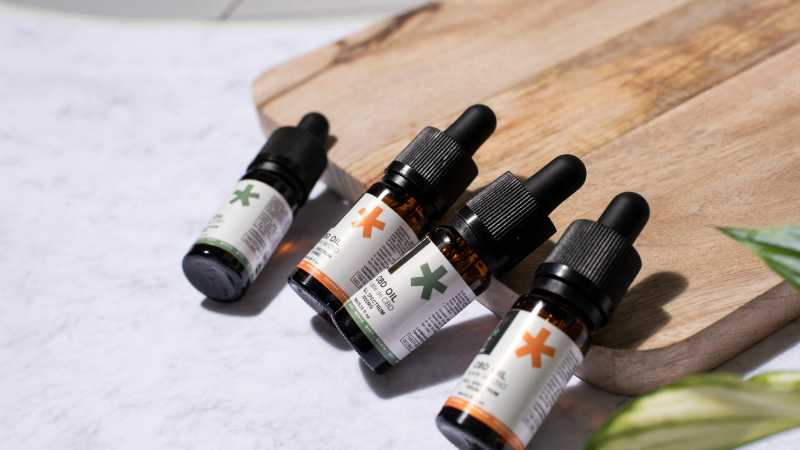 CBD oil bottles arranged on a wooden board with a natural leaf, perfect for holistic product promotion., tags: mit vollem für - pexel